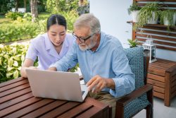 Carer assisting elderly service user to develop digital skills